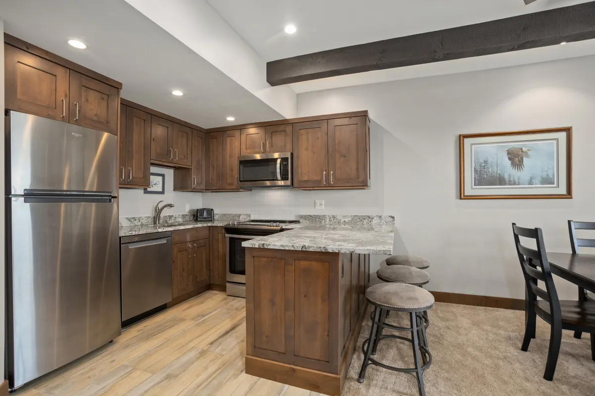A functional and stylish kitchen featuring stainless steel appliances, granite countertops, wood cabinetry, and an adjacent dining area. The setup is ideal for preparing and sharing meals with family and friends, with plenty of space for entertaining.